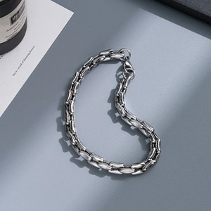 Close-up of a silver stainless steel chunky chain bracelet with lobster clasp on grey texture