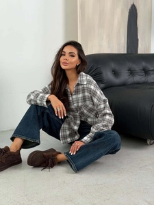 Close-up of black and white plaid shirt paired with dark blue wide-leg jeans and brown shoes