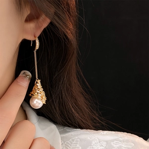 Détail de boucles d'oreilles pendantes dorées avec perles blanches sur mannequin