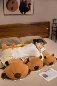 Multiple sizes of soft brown capybara plush pillows shown in a cozy bedroom scene