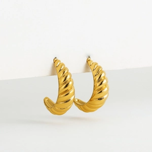 Macro detail of 18K gold plated hoop earrings featuring a textured croissant pattern