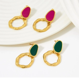 Detail of colorful enamel studs with textured gold wavy rings on a white tray