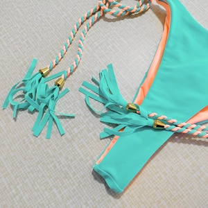 Detail of mint green bikini bottom with orange contrast and braided fringe tassels