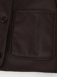 Detailed close-up of dark brown faux suede jacket with a large patch pocket and button