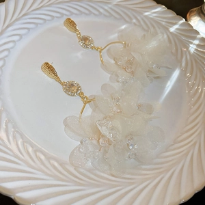 Detailed close-up of handmade tulle flower earrings with crystal accents on a ceramic plate
