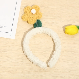 Close-up of soft white plush headband featuring a yellow tulip flower and green leaves