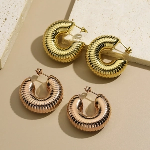 Detailed view of hollow C-shaped earrings with spiral texture in gold and rose gold