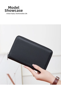 Close-up of black pebble grain leather wallet with silver zipper held by hand
