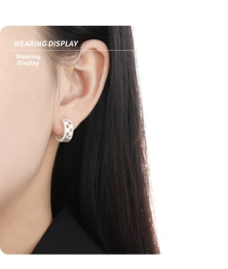 Wearing display of matte silver hollow checkered earrings with a modern round design