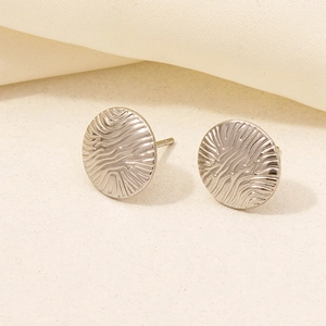 Close-up of silver geometric round stud earrings with unique irregular ripple texture