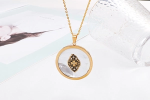 Macro detail of gold tree pendant with shell inlay and sparkling crystal accents
