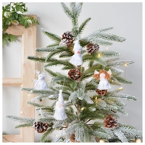 Detail of fabric angel, snowman, and pinecone ornaments on a snowy Christmas tree