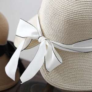 Elegant French straw sun hat with large white satin bow and black trim for summer beach