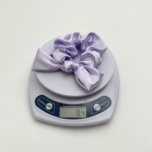 Detail shot showing the lightweight 9.4g weight of the light purple satin bow scrunchie