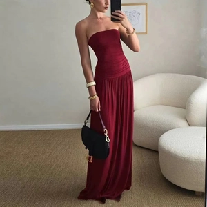 Detail of red strapless maxi dress featuring a ruched bodice and flowing pleated skirt