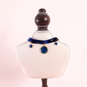 Detail of dark blue velvet pet collar with gold-trimmed star and moon charms