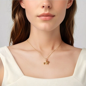 Close-up of a gold dachshund pendant necklace featuring a zircon-encrusted clasp on model