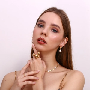 Close-up of model wearing 18K gold butterfly shell necklace with matching earrings