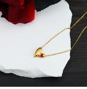 Macro d'un collier cœur doré avec détail en émail rouge et petit diamant blanc brillant
