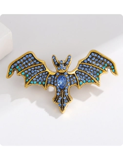 Macro detail of bat brooch featuring blue crystals and gold-tone alloy setting
