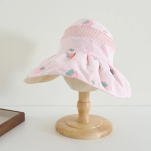 Détail d'un chapeau de soleil rose pour enfant avec motifs fraises et tissu résille