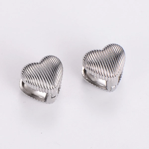Macro detail of silver heart hoop earrings featuring a polished vertical striped texture