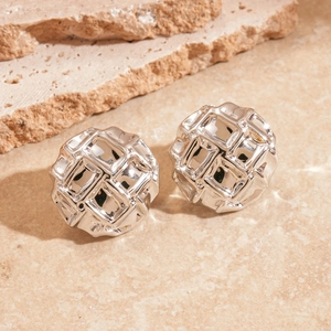 Vue macro de boucles d'oreilles rondes en métal argenté avec texture géométrique