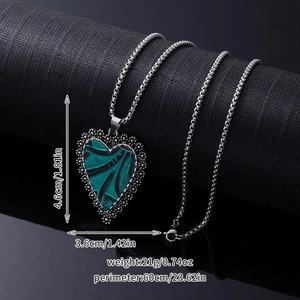 Detail of bohemian turquoise heart pendant with size and weight measurements on a dark stand