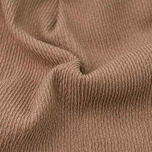 Macro shot of brown corduroy fabric texture showing vertical stripes and soft folds