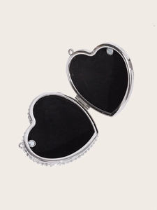 Detail of silver heart locket with rhinestones, open showing black velvet lining and magnet