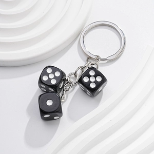Macro detail of high-quality metal keychain with three black dice charms on white background