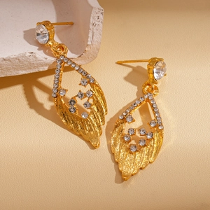 Elegant gold drop leaf earrings with inlaid crystals on a textured stone display