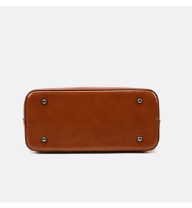 Detail view of brown leather bag bottom featuring four protective metal feet studs