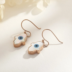 Rose gold Hamsa Hand earrings featuring evil eye detail on minimalist white background