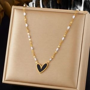 Gold-plated heart necklace with black enamel pendant on silk jewelry box surface