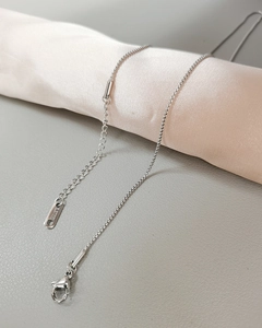 Detailed close-up of stainless steel box chain with lobster clasp on silk fabric