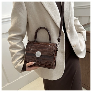 Close-up of deep brown crocodile embossed leather bag with silver metal round clasp