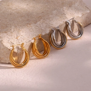 Detailed view of curved double-layered C-shaped earrings on a beige rock surface