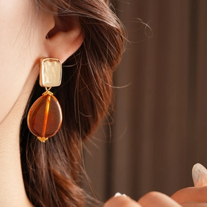 Detail of vintage square gold studs with amber resin teardrop pendants on model