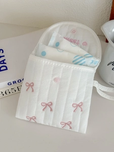 Detailed interior of white quilted pouch with sweet embroidery and bow accent