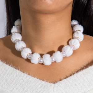 Gros plan d'un collier en pompons blancs et perles avec anneaux dorés sur mannequin