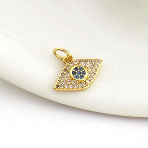 Macro shot of 18k gold plated evil eye charm with inlaid zircon and blue gemstone
