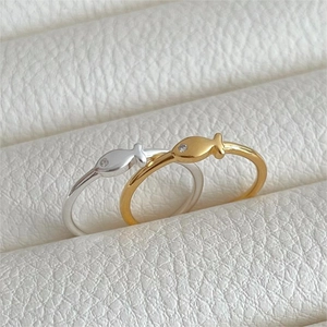 Dettaglio di anelli a forma di pesce in oro e argento con piccoli diamanti incastonati