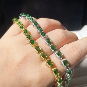 Detail of gold and silver tennis bracelets featuring oval green emerald-cut gemstones