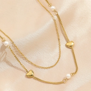 Double-layered gold titanium necklace with elegant pearls and heart pendants on pink silk
