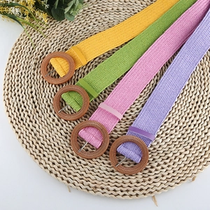 Detail of woven straw belts in yellow green pink purple with round buckle and metal pin