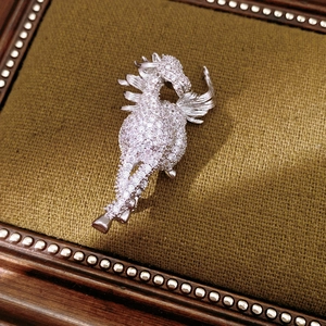 Macro shot of the winged Pegasus brooch with white zircons on olive green velvet