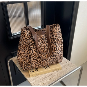 Détail du sac cabas en toile à imprimé léopard avec anses marron sur table en pierre