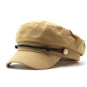 Detail of khaki cotton linen newsboy hat with black leather cord and gold button accent