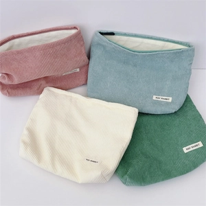 Detailed corduroy makeup bags in pink, blue, beige, and green with zipper closure